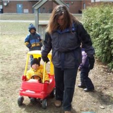 Children in a red cart being pulled around by a teacher.