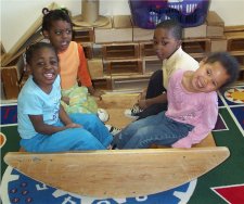 Four children playing on a see-saw in a classroom